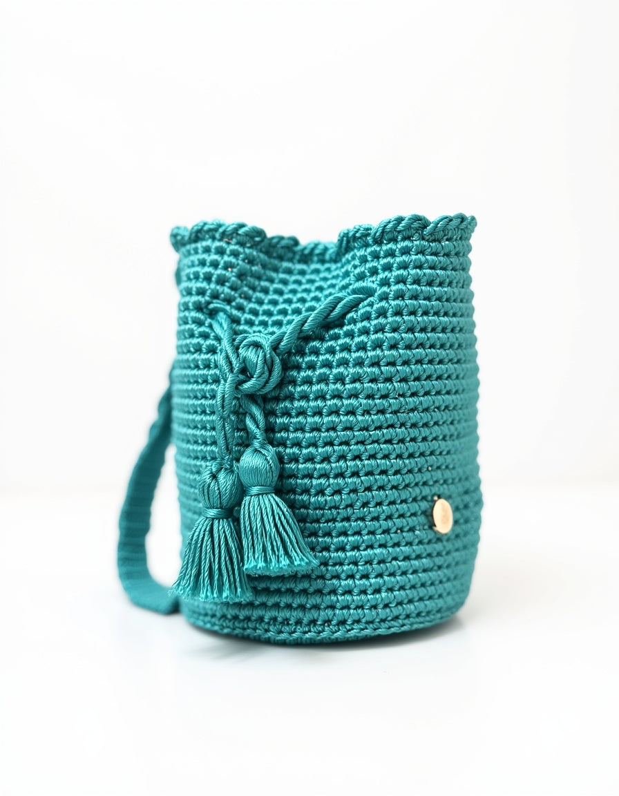Mochila Domenechsa color turquesa vibrante, diseño artesanal moderno con borlas decorativas y acabado elegante
