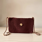 Bolso artesanal marrón bordó con cadena dorada elegante.