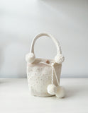 Mochila artesanal blanca de Domenechsa, decorada con perlas y pompones tejidos a mano