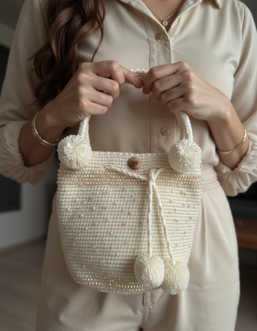 Vista frontal de una mochila blanca tejida con detalles de perlas y borlas, diseño exclusivo de Domenechsa.