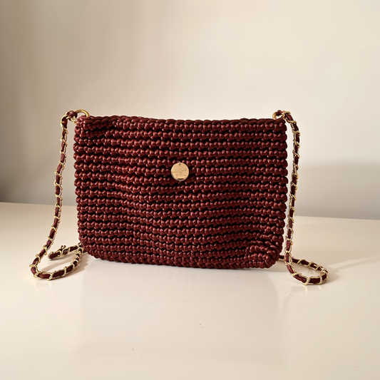 Mochila compacta bordó artesanal con cadena metálica.