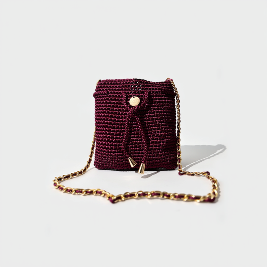 Mochila artesanal color borgoña con cadena dorada elegante.