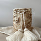 Mochila artesanal estilo boho Bronce Real, con cuentas, perlas y borlas tejidas a mano, ideal para outfits sofisticados.