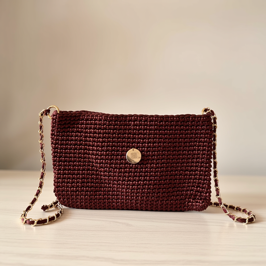 Bolso artesanal marrón bordó con cadena dorada elegante.