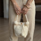 Mochila de mano con diseño circular y detalles de perlas y borlas, estilo delicado y artesanal.
