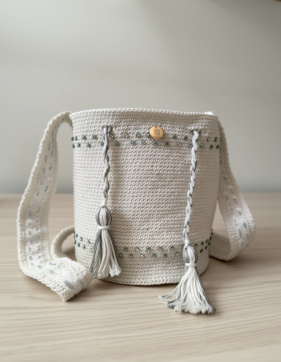 Vista frontal de la mochila Perla Boreal, con trenzas y pompones decorativos.