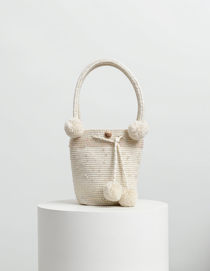 Bolso blanco con asa firme y perlas brillantes, hecho a mano por artesanos de Domenechsa.