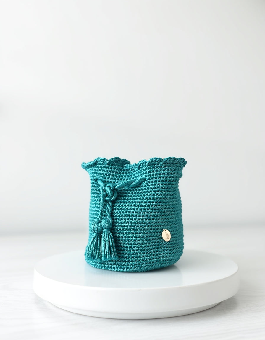 Bolso tipo mochila en tono esmeralda turquesa, hecho a mano con detalles de nudos, borlas y tejido grueso