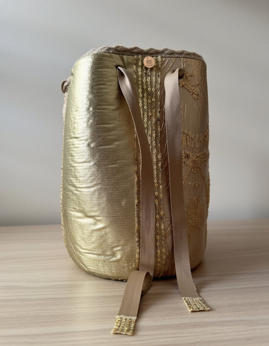 Mochila artesanal en tono dorado imperial con cintas satinadas y acabado elegante de Domenechsa.
