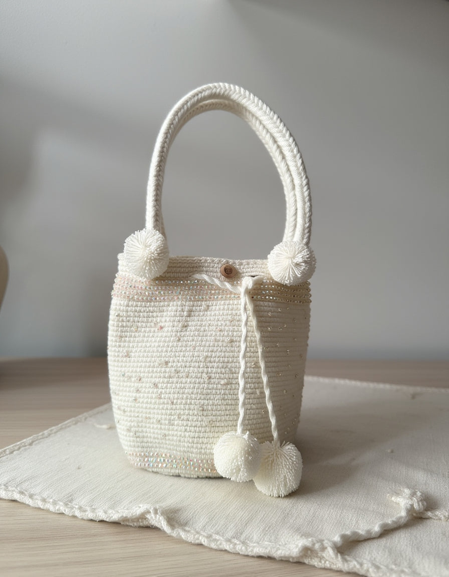 Bolso artesanal en tono blanco con textura fina y perlas de adorno, hecho a mano con estilo.

