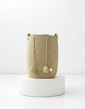 Mochila artesanal Domenechsa en tono oro tierra, tejida a mano con pompones decorativos.