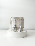 Mochila artesanal en tonos perla y gris con borlas decorativas, diseño Perla Boreal de Domenechsa.