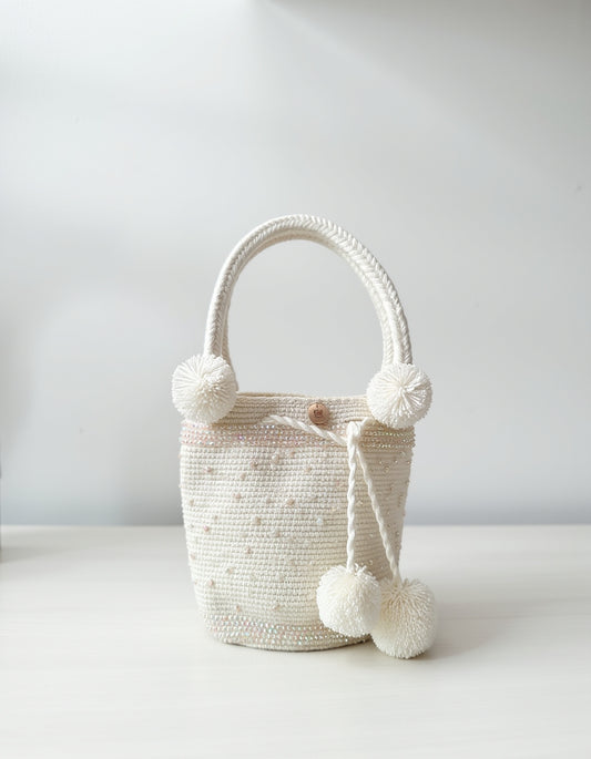 Mochila artesanal blanca de Domenechsa, decorada con perlas y pompones tejidos a mano